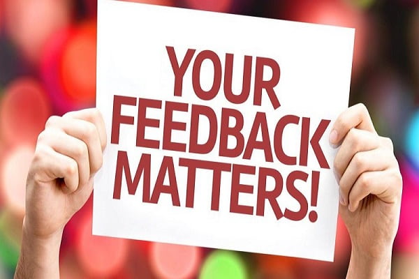 Manos levantando un cartel que dice en inglés: ¡Tu feedback importa!